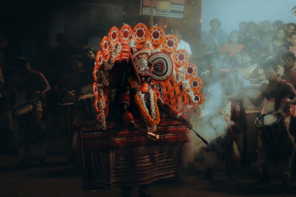 Theyyam performer in an ornate headdress at a night temple festival near Kozhikode, Kerala