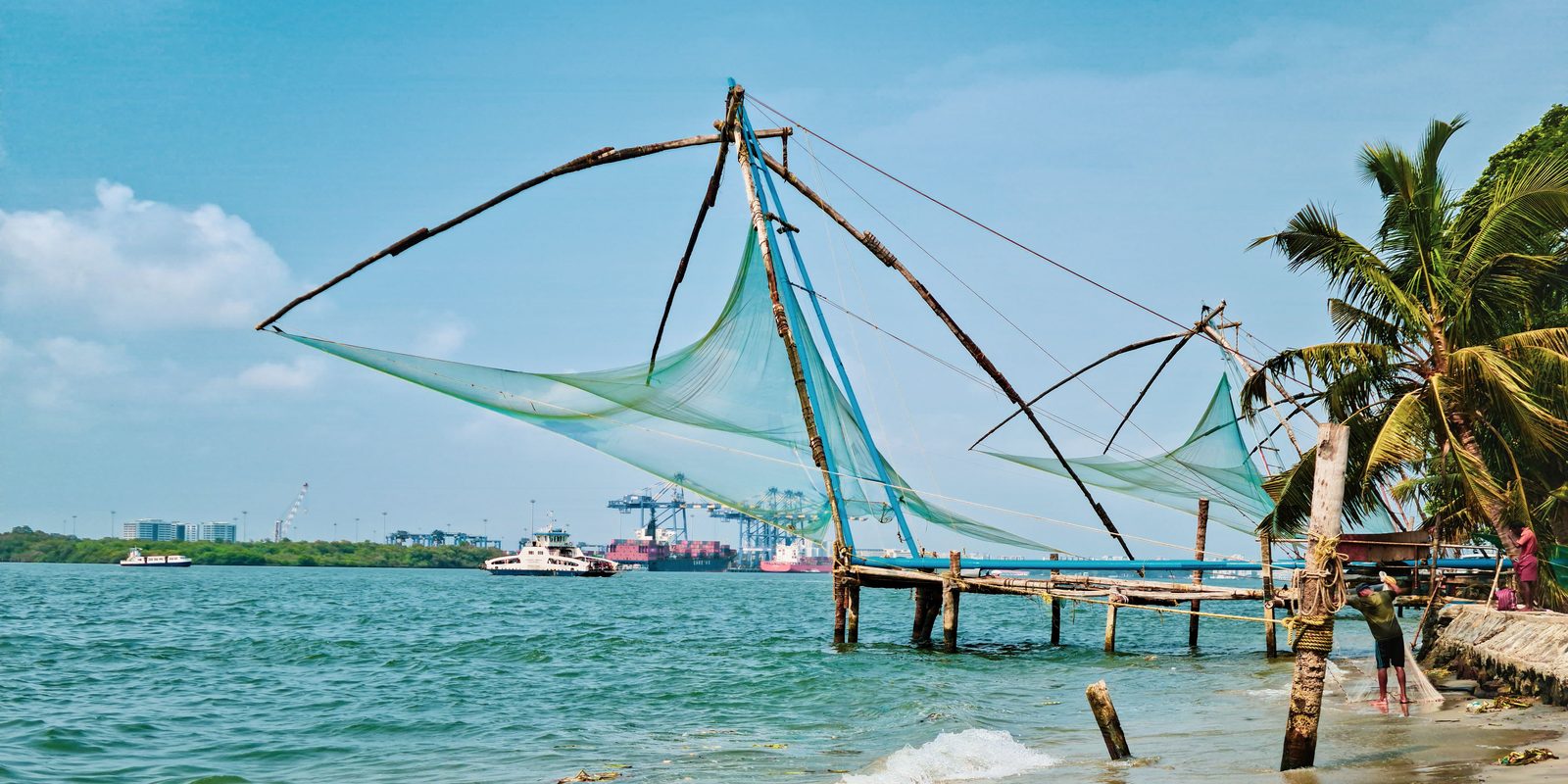 Chinese fishing nets on the shore at Fort Kochi, Kerala, with the container port behind